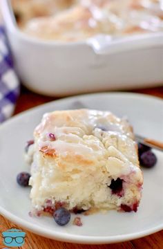 a piece of blueberry cheesecake on a white plate with a fork next to it