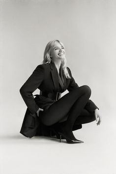 a black and white photo of a woman sitting on the ground with her legs crossed