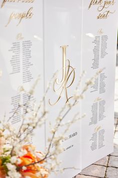 wedding seating chart with white flowers and gold lettering on the back wall for guests to sign