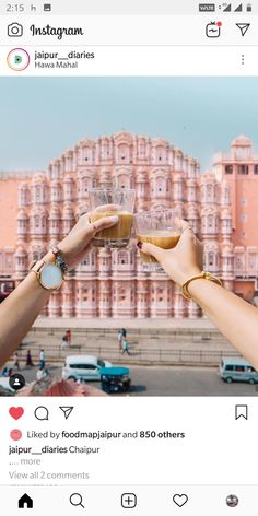 two people toasting with wine glasses in front of a pink building on instagram