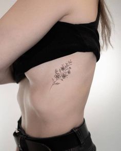 a woman's stomach with a flower tattoo on her left side ribcage