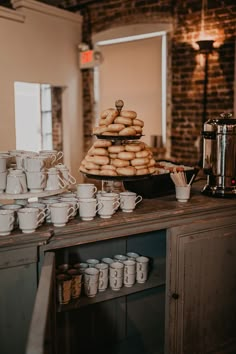 a stack of donuts sitting on top of a table next to cups and saucers