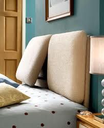 a bed with two pillows on top of it next to a night stand and lamp