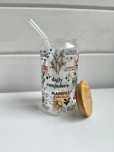 a glass jar with a wooden lid is sitting on a white surface and has words all over it