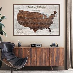 a map of the united states is hanging on a wall above a wooden cabinet in a living room