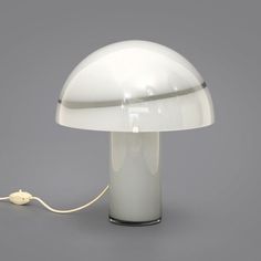 a white table lamp sitting on top of a gray floor