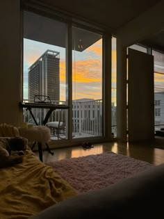 a living room filled with furniture and large windows overlooking the cityscape at sunset