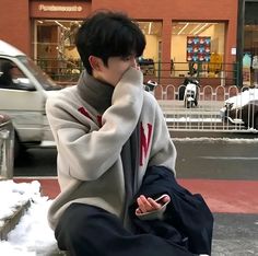 a young man sitting on the curb using his cell phone