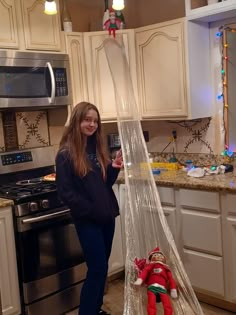 a woman standing in a kitchen next to an upside down christmas tree with decorations on it