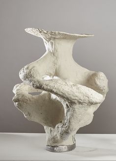 a white sculpture sitting on top of a table next to a gray wall and floor