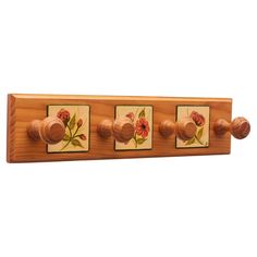 a wooden coat rack with four knobs and flowers painted on the front, along with two matching wood pegs