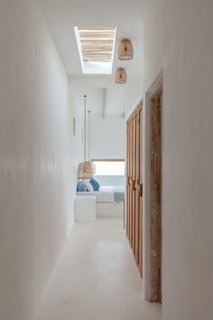 an empty hallway leading to a bedroom with white walls and ceiling lights hanging from the ceiling