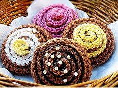 four crocheted flowers sitting in a wicker basket