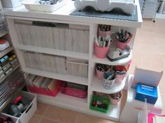 a white shelf filled with lots of crafting supplies and storage bins next to a sink