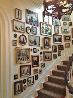 a staircase with many pictures on the wall and a chandelier hanging above it