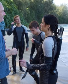 a group of people standing next to each other in wetsuits and holding knives