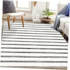 a white and black striped rug in a living room with a plant on the floor