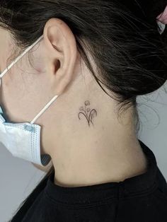 a woman wearing a face mask with a small flower tattoo on her left side neck