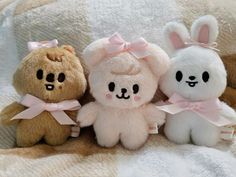 three stuffed animals sitting next to each other on a blanket