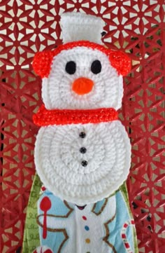 a crocheted snowman with a red hat and scarf on it's head