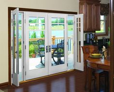 an open patio door in a kitchen with wooden cabinets and wood flooring on the side