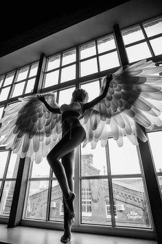 a woman with wings standing in front of a window