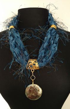 This ribbon scarf/necklace is made with a variety of specialty ribbons and yarns from around the world. Done in shades of blue a   This ribbon scarf necklace come with gold jewelry and an interchangeable pendant.  This is a ResQ™ product so 10% of the profits go to help the fight against human trafficking.  FREE SHIPPING Ribbon Scarf, Textile Necklace, Ways To Wear A Scarf, Color Trends Fashion, Scarf Necklace, Ribbon Necklace, Chair Decorations, Ann Arbor, Scarf Jewelry