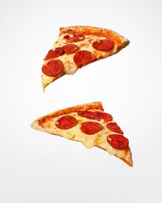 two slices of pepperoni pizza are flying in the air, one slice is upside down