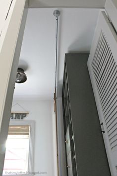 an overhead view of a closet with white shutters and gray shelves, along with a light fixture in the corner