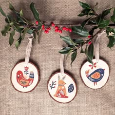 three wooden ornaments hanging from a tree branch