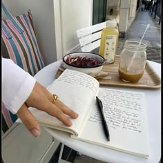 a person is sitting at a table with an open book and some jars on it