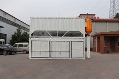 a large white container sitting in the middle of a parking lot next to a building