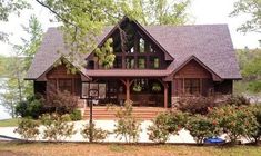 a large house with lots of windows and flowers in the front yard, surrounded by greenery