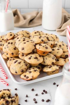 chocolate chip cookies and candy canes on a white plate with milk in the background