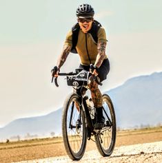 a man riding a bike on top of a dirt road in the middle of nowhere