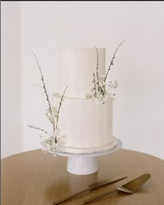 a white wedding cake sitting on top of a table next to a knife and fork