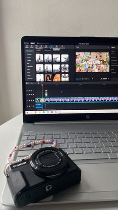 an open laptop computer sitting on top of a white table next to a small camera