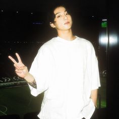 a man standing in front of a soccer field giving the peace sign with his hand