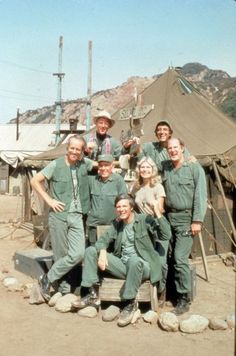 a group of people posing for a picture in front of a camouflage background with the words mash on it