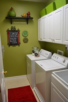 a laundry room with green walls and white cabinets