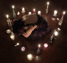 a woman laying on the floor surrounded by candles