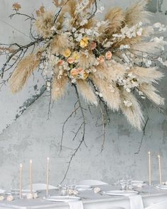 the table is set with white linens and tall pamodia branches, which are adorned with flowers