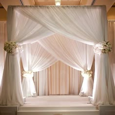 a decorated stage with white drapes and flowers