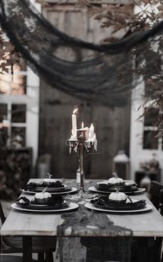 the table is set with black plates and candles