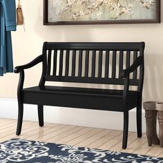 a black bench sitting in front of a painting on the wall next to a blue rug