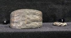 two ancient bracelets are sitting next to each other on a black cloth covered bench