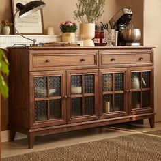 a wooden cabinet with glass doors in a living room next to a potted plant