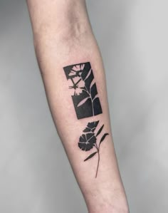 a black and white flower tattoo on the left arm, with an image of a plant behind it