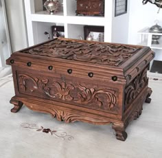 an ornate wooden box sitting on top of a white rug in front of a bookshelf