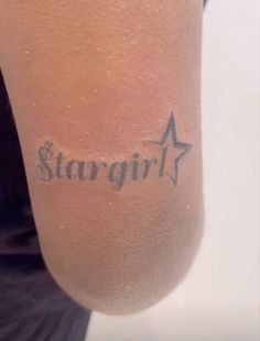 a woman with a star tattoo on her arm and the word stargirl written in cursive ink